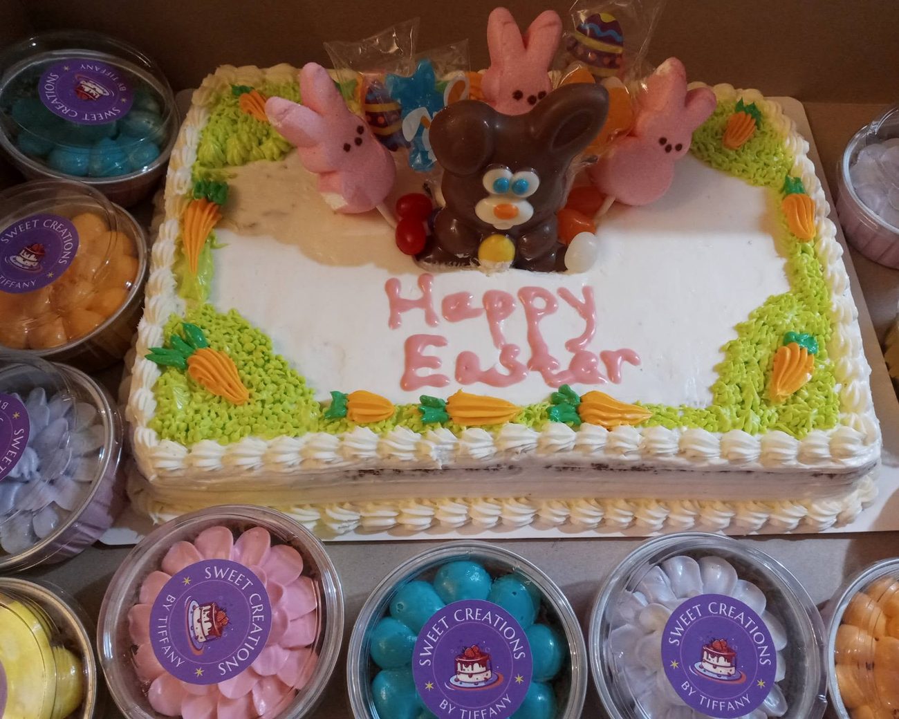 A decorated Happy Easter sheet cake surrounded by branded Sweet Creations dessert cups — a custom catering spread